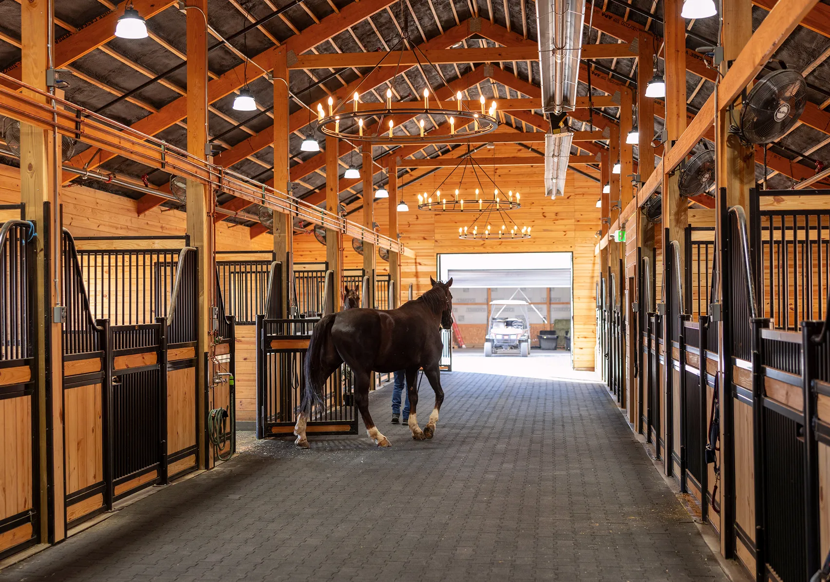 Interior of the SkyRidge Equestrian barn featuring spacious horse stalls, wide aisles, and natural wood finishes.