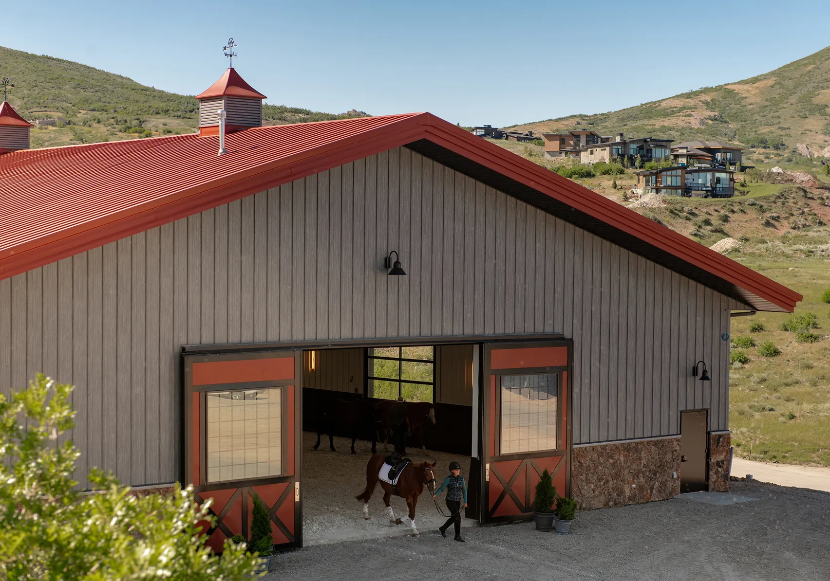 Modern horse barn with open stalls overlooking the rolling hills of SkyRidge Equestrian.